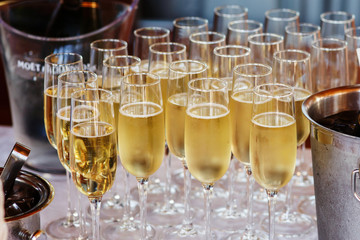 Full cold champagne flutes stand between buckets on dinner table