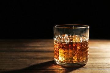 Glass of whisky on wooden table closeup