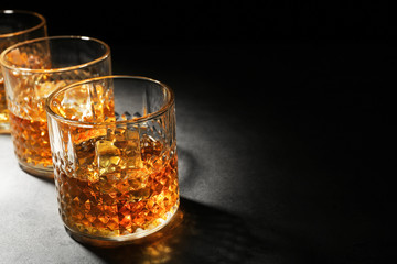 Glasses of whisky on grey textured table closeup