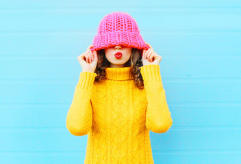Fashion happy woman blowing red lips makes air kiss wearing a kn