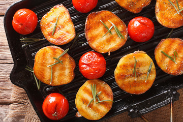 roasted potatoes and tomatoes with rosemary close up on a grill pan. Horizontal top view