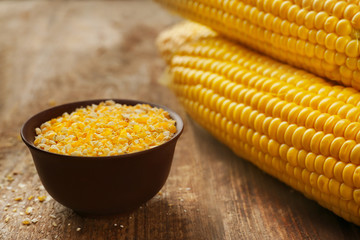 Ground corn seeds and in bowl on wooden table, closeup