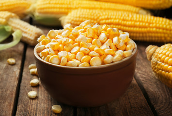 Corn seeds in bowl on wooden table, closeup