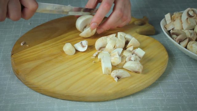 The girl shef in the kitchen sliced mushrooms clean the mushrooms. Cutting on a wooden board.
