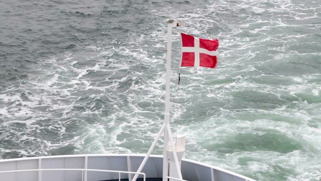 Danish flag closeup waving in the wind on the stern of the ship. The ferry sails from Denmark to Sweden and back