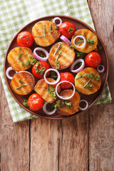 Healthy food: grilled potatoes and tomatoes with herbs and onion close-up on a plate. Vertical top view