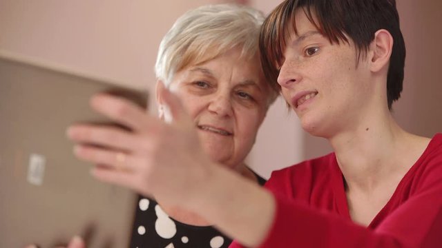 grandmother and her daughter take a selfie with tablet