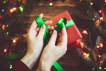 Woman tie a bow on a gift box. Christmas preparing concept.