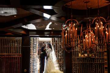Bride and groom in military uniform stand kissing among shelves