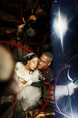 Fototapeta na wymiar Look from above at happy wedding couple hugging on spiral stairs