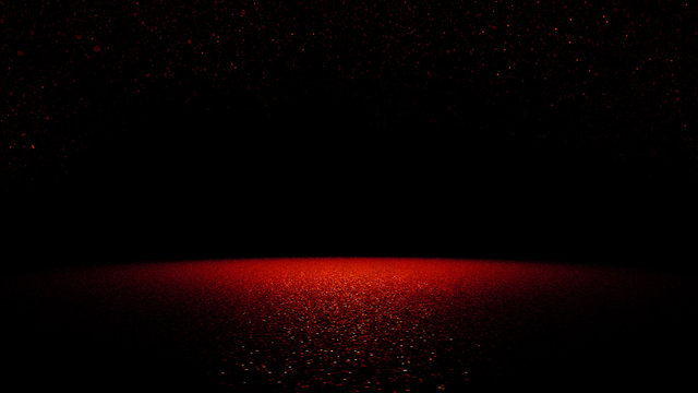 twinkling red glitter falling on a flat surface lit by a bright spotlight