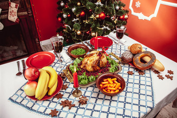 Christmas dinner by candlelight, table setting. Thanksgiving table with baked turkey in a decorated room with a Christmas tree.