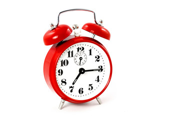 A quarter past seven shows an old round red alarm clock on white background - isolated. 