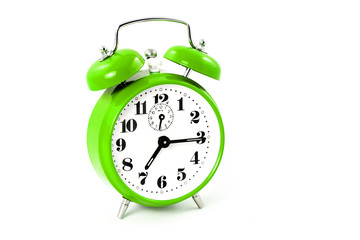 Round green alarm clock on white background isolated. The image of the retro clock shows a quarter past seven.