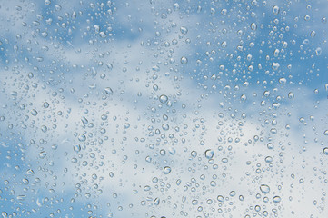 Naklejka na ściany i meble Raindrops on the window blue sky background 