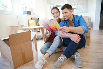 Cheerful couple moving in new home, choosing wall paint colours