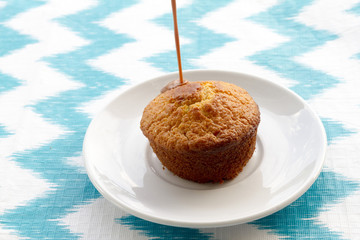 Chocolate is poured onto cake at plate on striped background. To