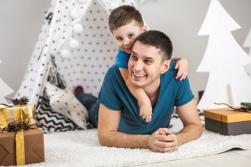 Dad and son home decorated for Christmas, give gifts, laugh, play, indulge