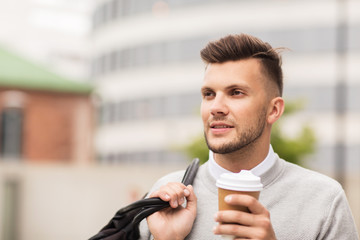 young man with bag drinking coffee in city