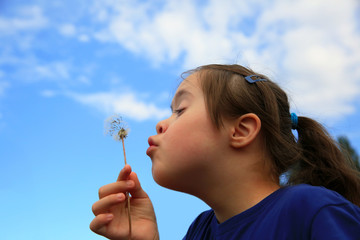 Little girl blowing dandelion