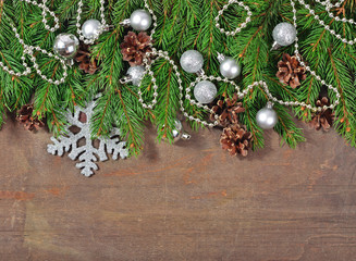 Silver Christmas decorations and spruce branch and cones on a wo