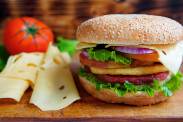 Burger with tomato and cheese on the table of the old village boards