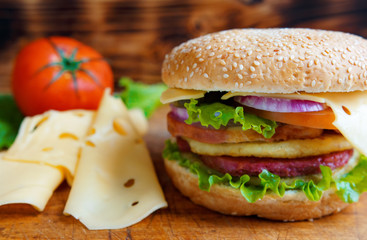 Burger with tomato and cheese on the table of the old village boards