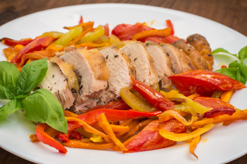 Roast duck breast with vegetable saute on a square plate. Wooden background. Top view. Close-up