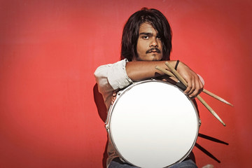young drummer holding sticks and snare isolated on red backgroun