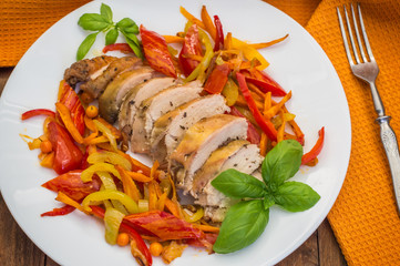 Roast duck breast with vegetable saute on a square plate. Wooden background. Top view. Close-up