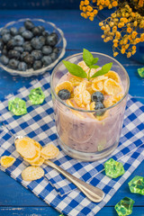 Blueberry Yogurt, cereal and a sprig of mint. Wooden blue background. Top view. Close-up