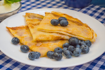 Pancakes with blueberries, whipped cream and a sprig of mint  lemon balm. Wooden blue background. Close-up.