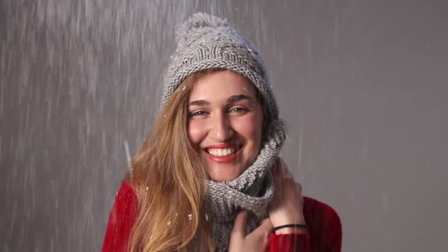 joyful beautiful young woman laughing in snowfall for a warm winter