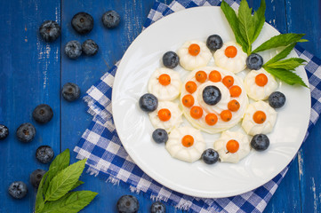 Blueberries and buckthorn laid out in the shape of a heart with cream meringue. Wooden background. Top view. Close-up