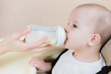 mother feeds her nine-month baby milk house