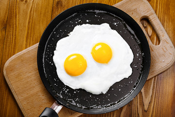 Fried eggs meal in a frying pan for delicious healthy breakfast. Traditional international breakfast food, top view.