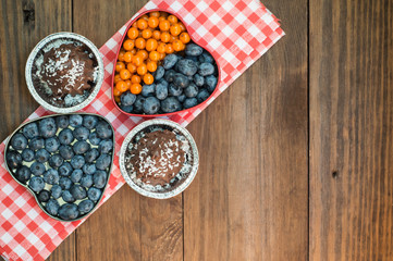 Blueberries and buckthorn laid out in the shape of a heart  chocolate truffles. Wooden background. Top view. Close-up