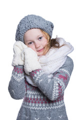 Happy cute kid posing in the studio isolated on white background. Wearing winter clothes. Knitted woolen sweater, scarf, hat and mittens.