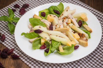 Chicken salad, pears, dried gooseberries and currants, cheese on basil leaves. Wooden background. Top view. Close-up
