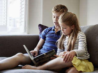 Two children sitting side by side reading  book