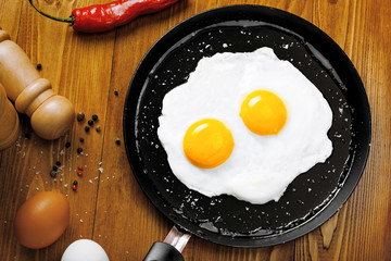 Healthy quick breakfast made of two fried eggs on a table. Traditional simple food on a frying pan for eating. Top view.
