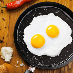 Traditional healthy easy quick breakfast meal made of two fried eggs served on a frying pan. International simple food, top view.