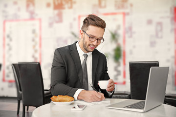 Young businessman working in cafe while having snack