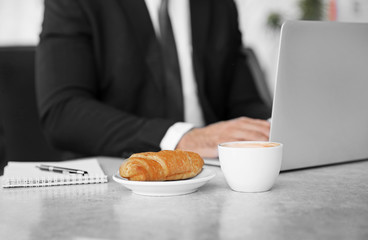 Cup of coffee and plate with tasty pasty on table, close up view