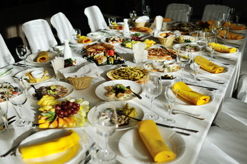served banquet table with dishes and snacks - pizza, rolls, fruit, meat, sausage, sliced, Assorted