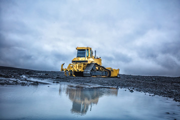 Bright yellow bulldozer against the cloudy sky in highland. Summer 2016 Iceland - obrazy, fototapety, plakaty