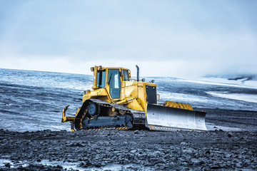 Bright yellow bulldozer against the cloudy sky in highland. Summer 2016 Iceland - obrazy, fototapety, plakaty