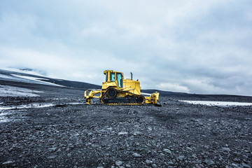 Bright yellow bulldozer against the cloudy sky in highland. Summer 2016 Iceland