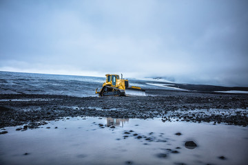 Bright yellow bulldozer on a gray plateau. Summer in 2016 Iceland