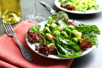 Tasty salad with Brussels sprouts and lettuce on grey table